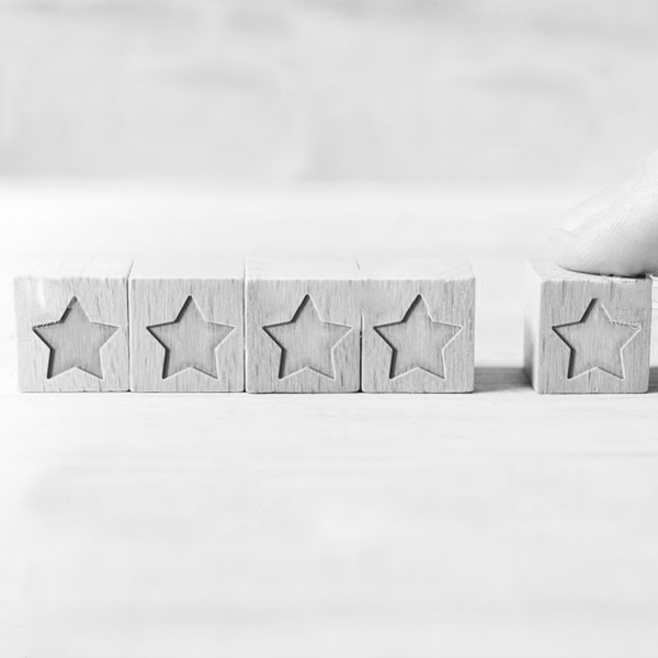 Image symbolisant le produit de qualité, cinq cubes en bois avec des étoiles gravées dessus Produit de qualité